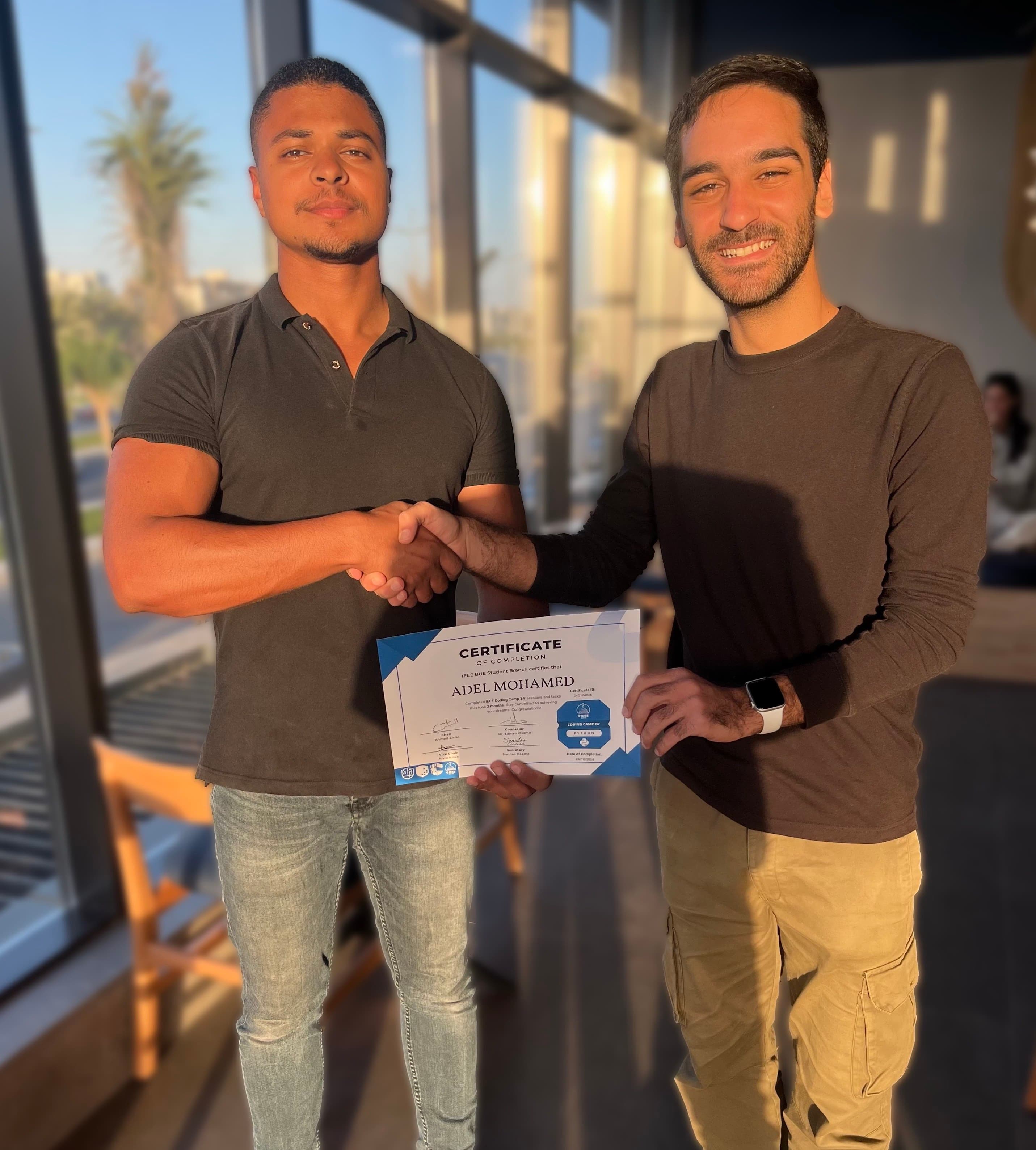 Adel with IEEE BUE Student Branch president Ahmed El-Sisi while holding the Python Coding Camp certificate